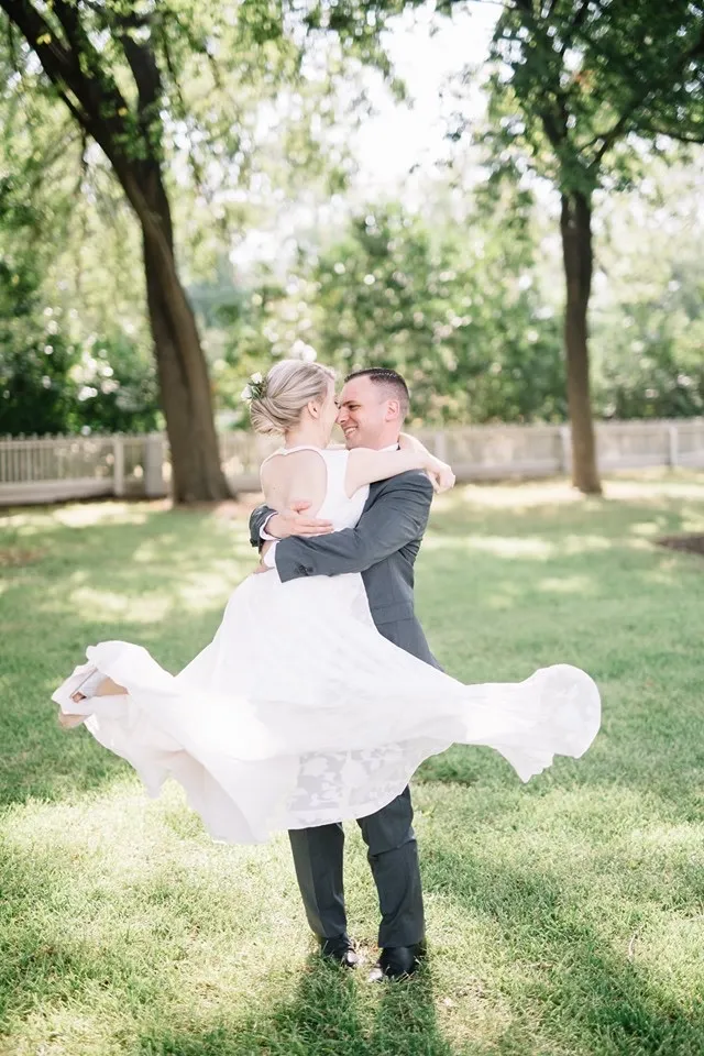 a groom holds his bride as he spins her around