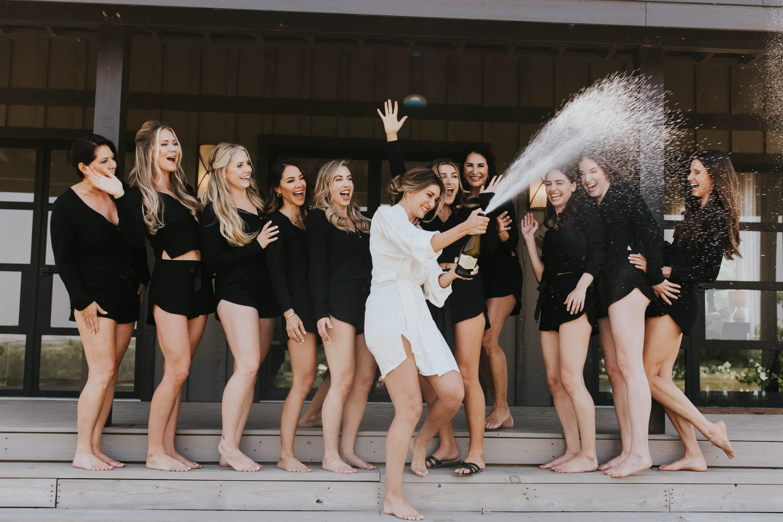 a bride in a white rode stands with her friends who wear black robes