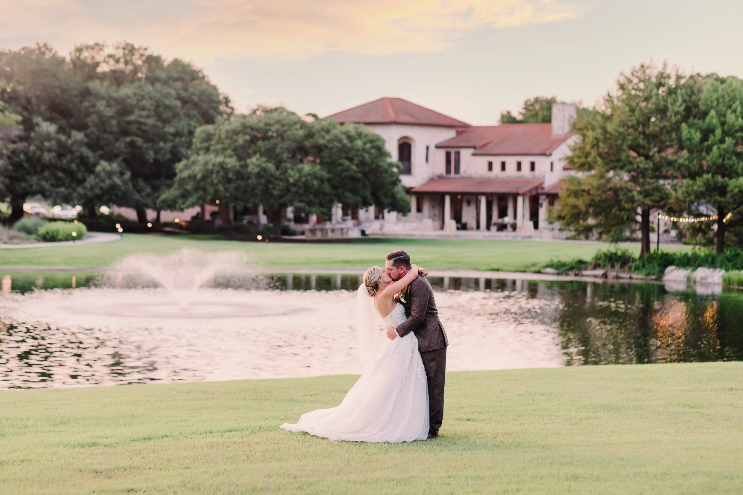 a far away photo of a bride and groom kissing in front of a pond