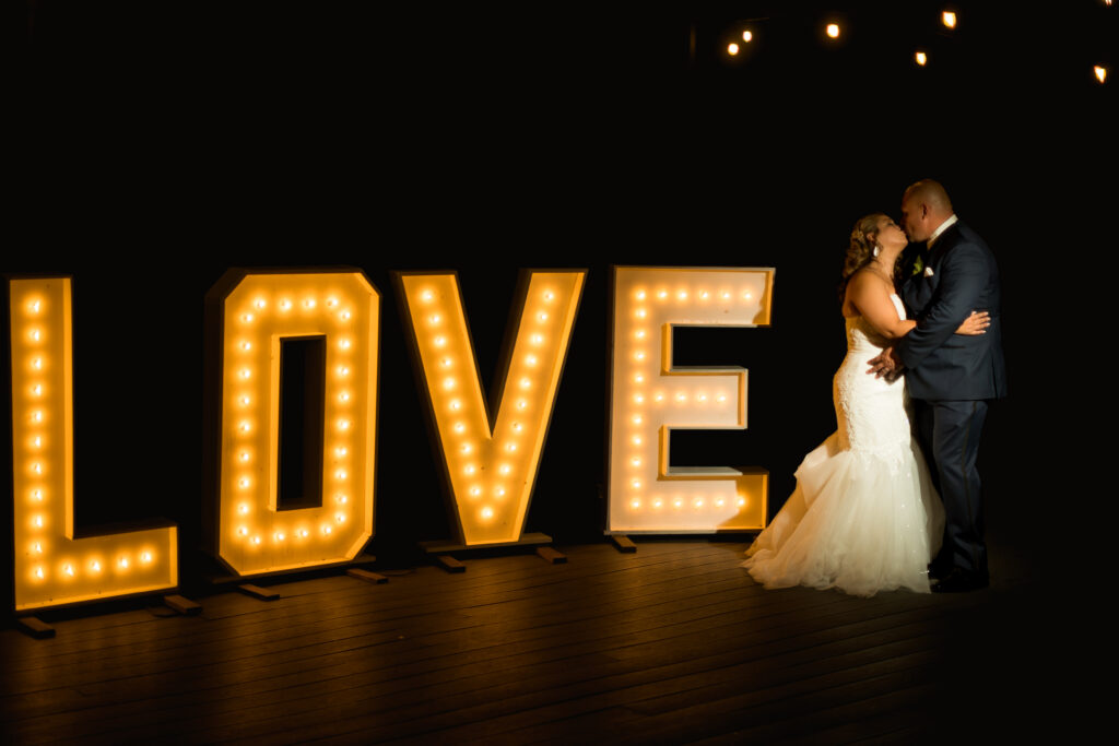 A newly married couple post in front of a LOVE sign, set up by their wedding planner