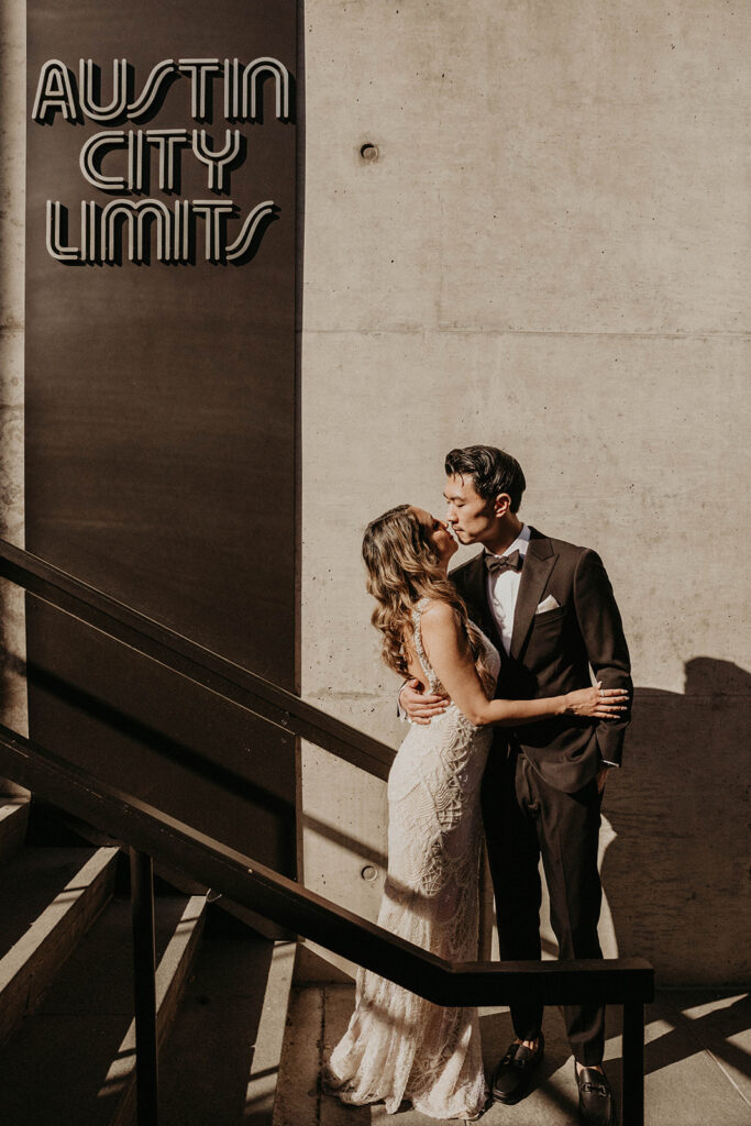 a bride and groom kiss on stairs outside Austin City Limits building